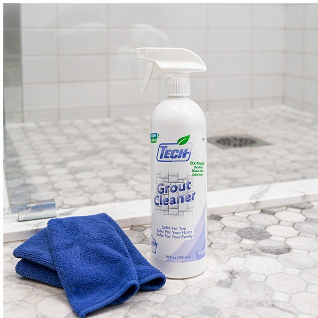 Tech Grout Cleaner bottle with a blue towel on a tiled bathroom floor.